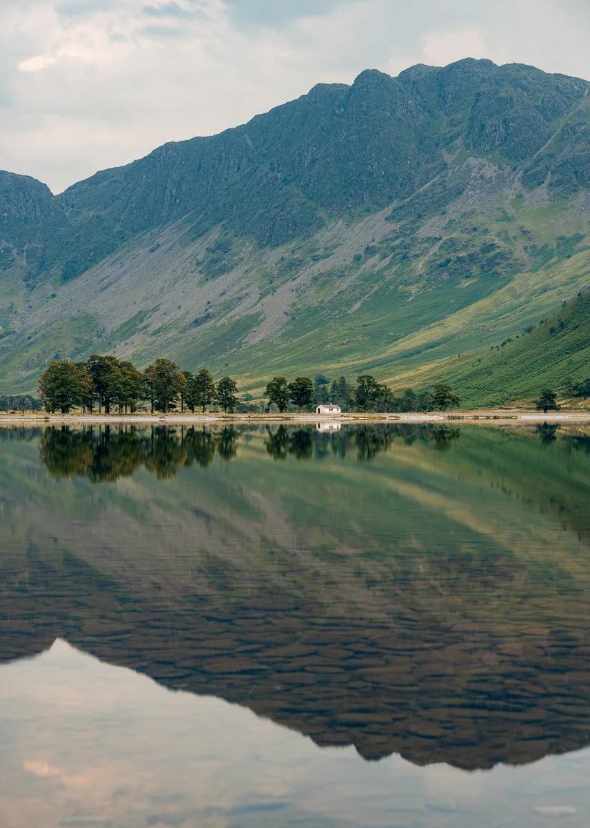Buttermere in the Lake District National Park, steep green slopes reflected in the water