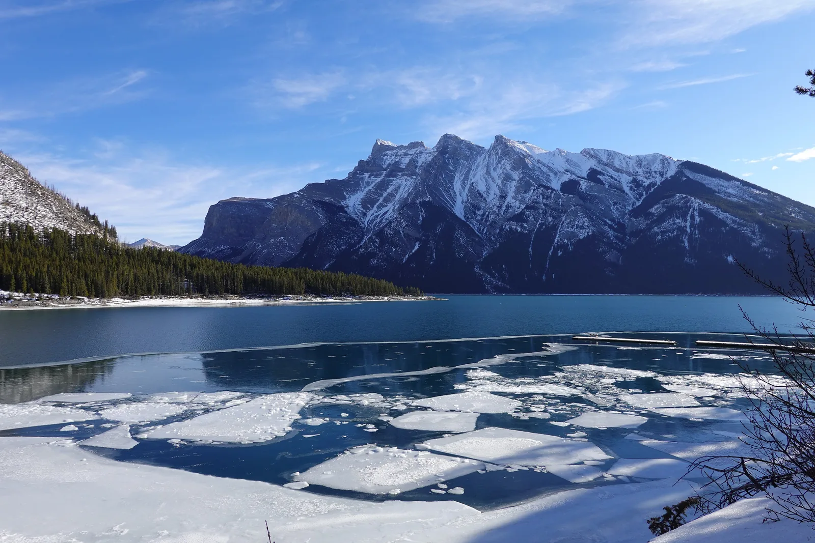 Lake Minnewanka in Banff National Park in winter: ice floes on dark blue water, Mount Girouard and Mount Inglismaldie behind.