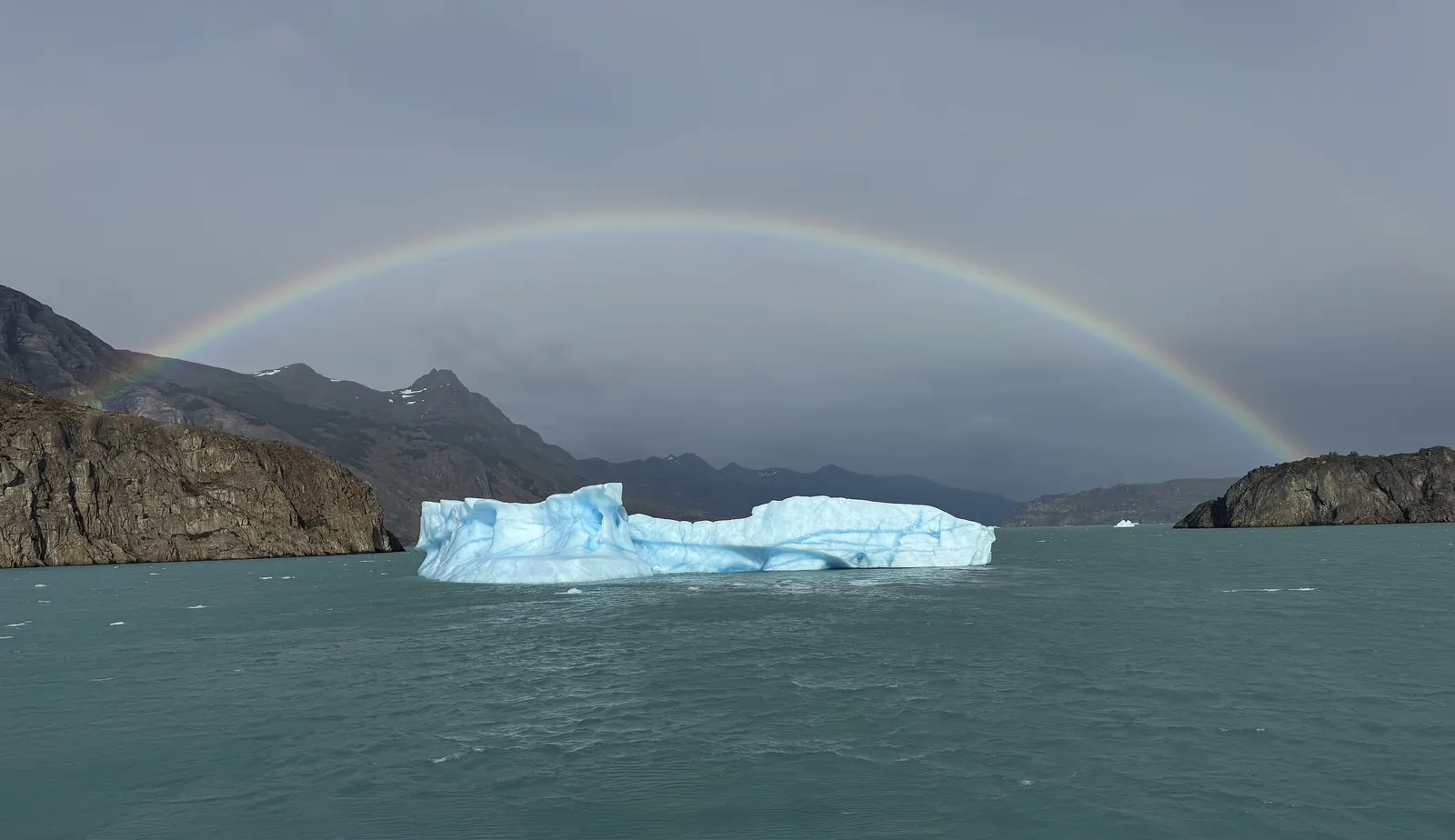 A rainbow arches over a blue iceberg on Lago Argentino near Puerto Bandera in Los Glaciares National Park