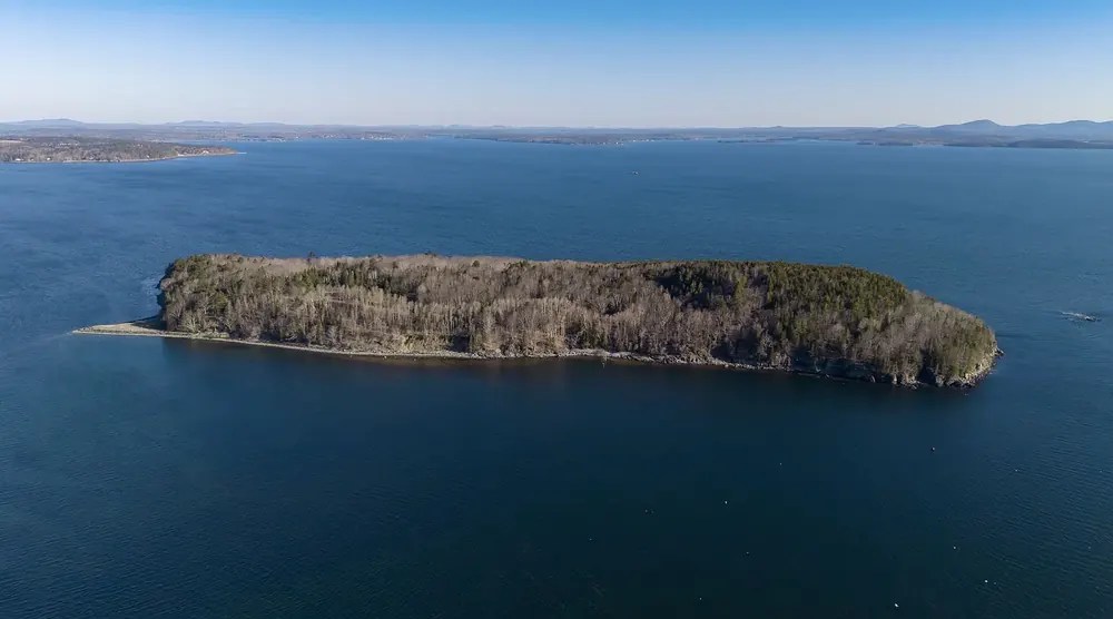 Aerial view of Bar Island in Acadia National Park: a wooded, uninhabited tidal island in deep blue water off Bar Harbor