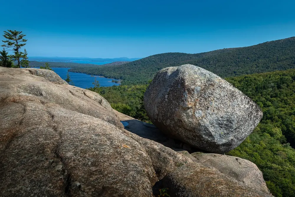 Bubble Rock in Acadia National Park: a large granite erratic on the edge of South Bubble, with a long lake and wooded hills behind