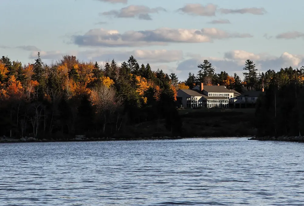 Jordan Pond in Acadia National Park in evening light, with the Jordan Pond House restaurant building on the wooded shore in autumn colours
