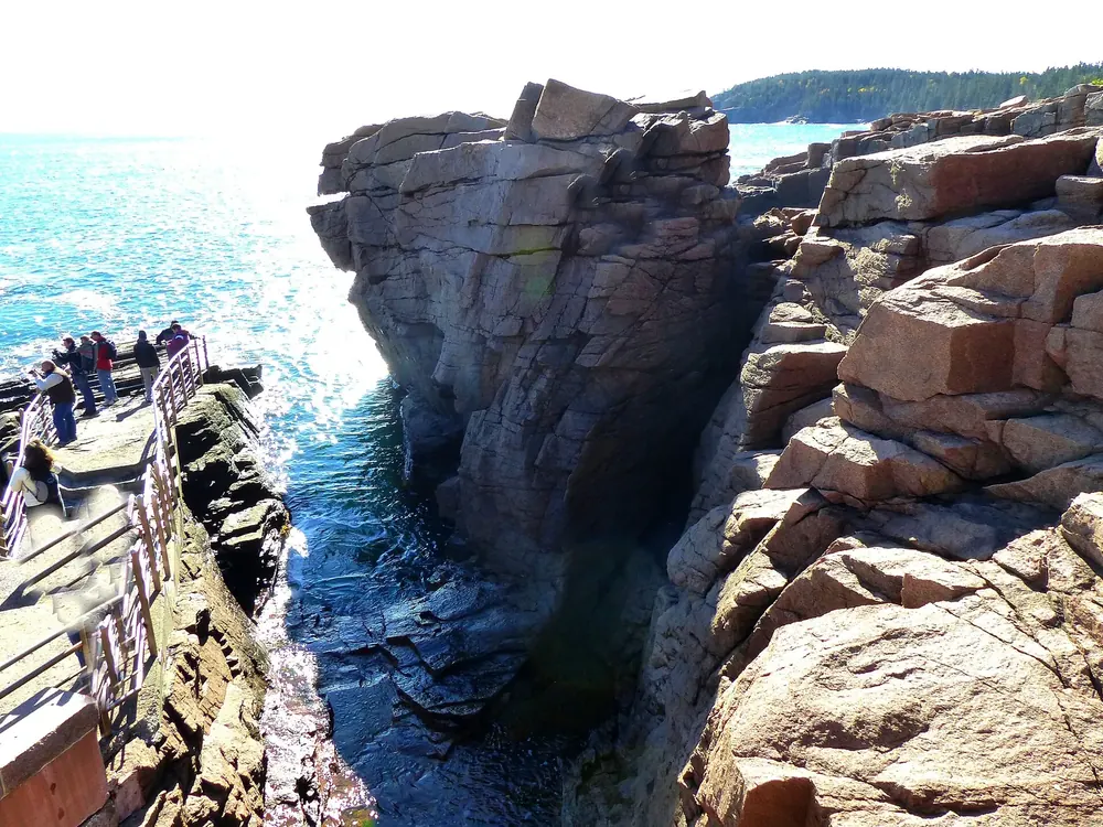 Thunder Hole in Acadia National Park: a narrow chasm in pink granite, with the railed viewing platform above the surf on the left
