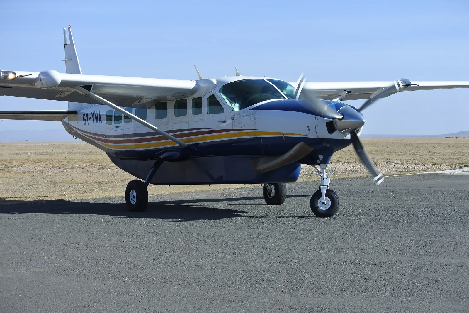 A single-engine light aircraft on the tarmac airstrip in Amboseli National Park, with the flat, dry plain behind