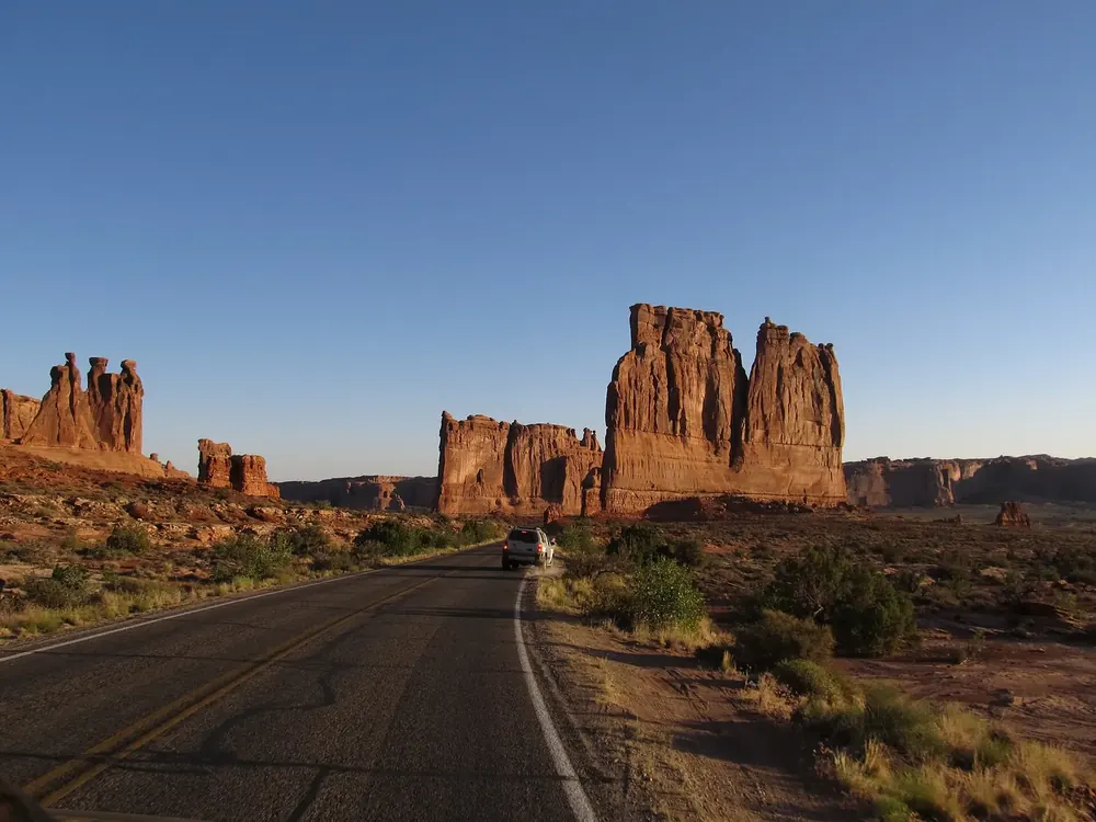 Red sandstone towers of the Courthouse Towers in Arches National Park, with The Organ and the Three Gossips, the park road in front in evening light