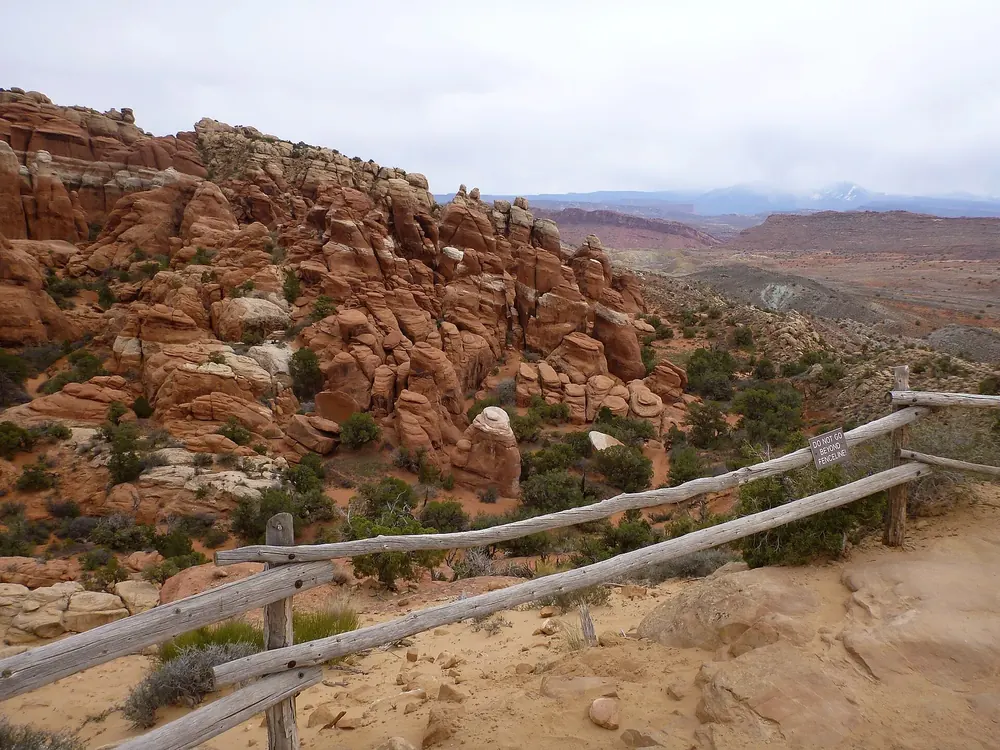 View from the viewpoint in Arches National Park over the maze of reddish sandstone fins in the Fiery Furnace, a wooden fence in front