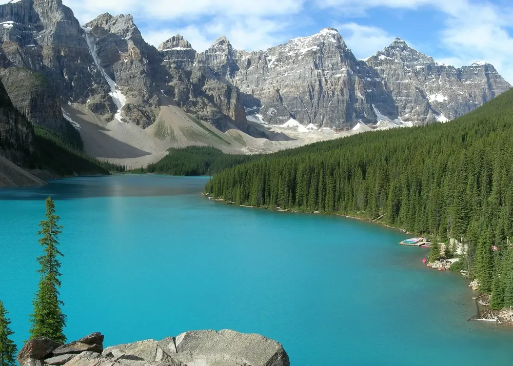 Turquoise Moraine Lake in Banff National Park from the viewpoint on the north shore, a chain of rugged, partly snowy peaks behind.