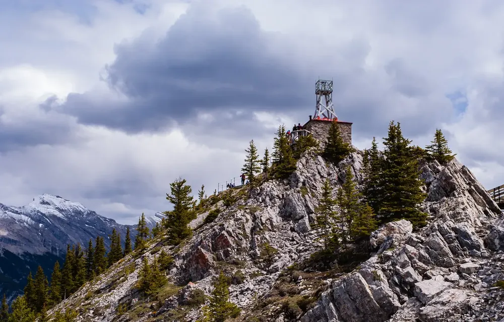 Summit of Sanson Peak in Banff National Park on Sulphur Mountain with the stone observatory of the historic site, surrounded by rocks and spruces.