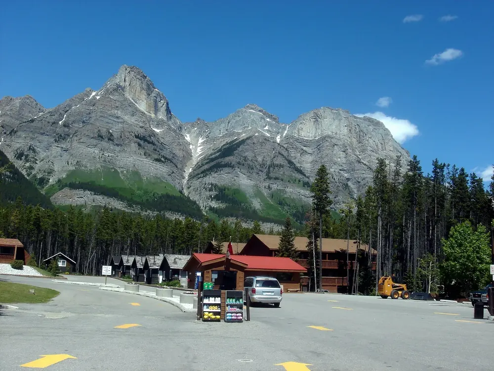 Saskatchewan River Crossing: roadside stop with red roofs, petrol pumps and a parking lot below rugged limestone peaks