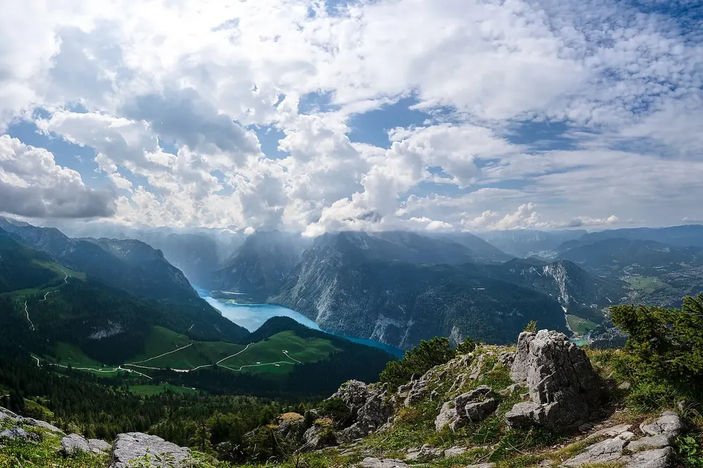 View from the summit of the Jenner over rocks and alpine pastures down to Lake Königssee between steep mountainsides