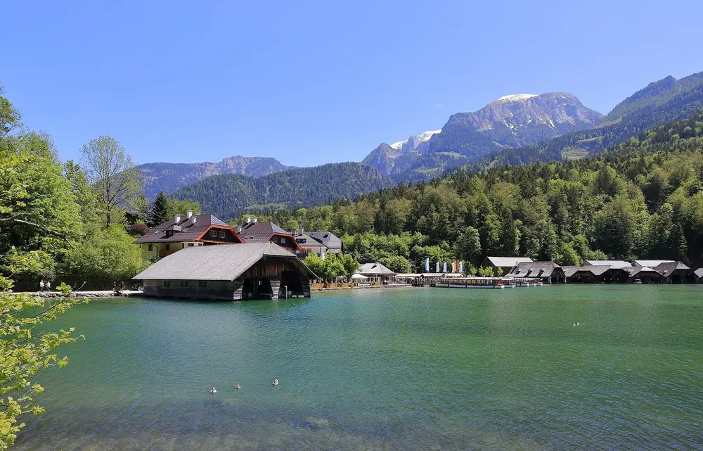 Lake Königssee near Schönau: boathouses on the green shore, wooded slopes and peaks of the Berchtesgaden Alps behind