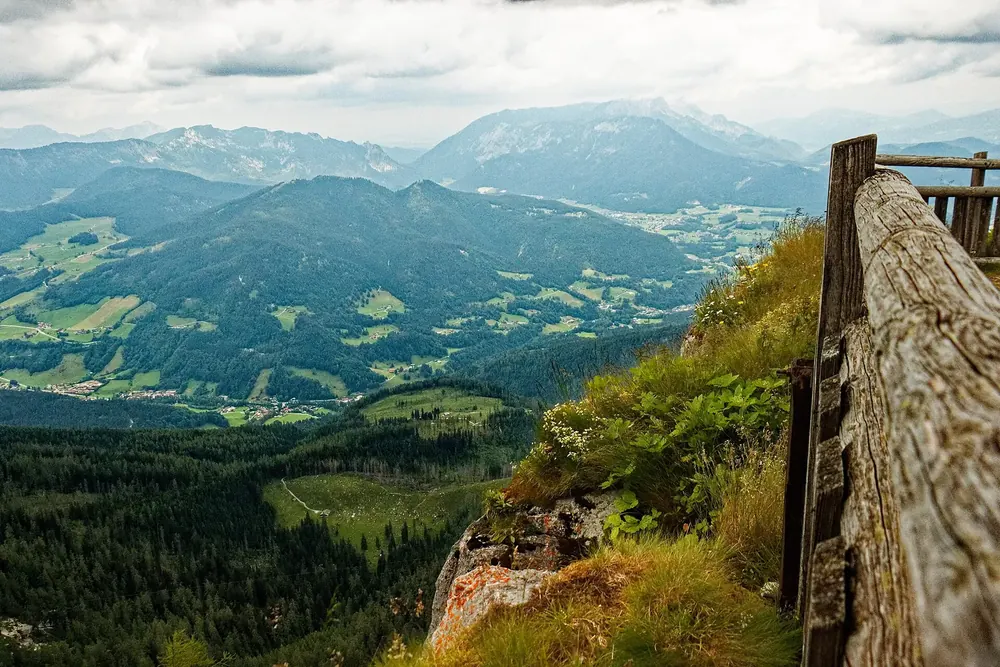 View from the Watzmannhaus in Berchtesgaden National Park over the wooden terrace railing down into the valley and distant mountain ranges