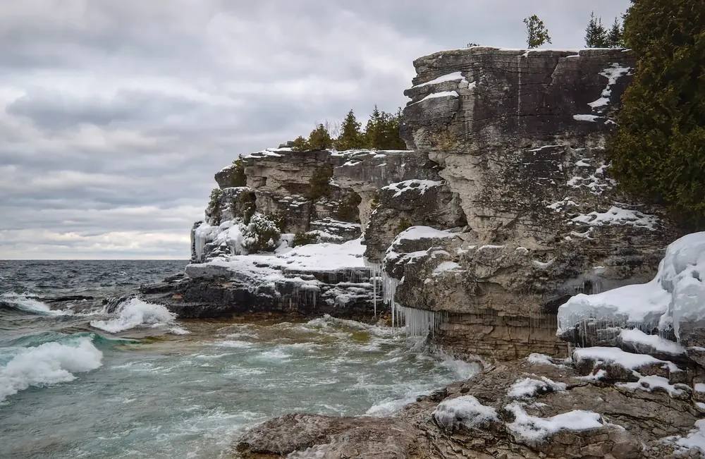 Limestone cliffs of Indian Head Cove in Bruce Peninsula National Park in winter, ice on the rocks and foaming surf on the shore