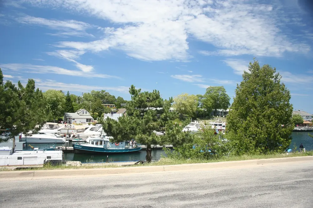Tobermory harbour with boats and docks, lined with trees and houses under a blue sky