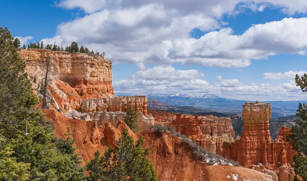 View from the Agua Canyon Overlook in Bryce Canyon National Park of cliffs and hoodoos with fresh snow, snow-covered mountains on the horizon