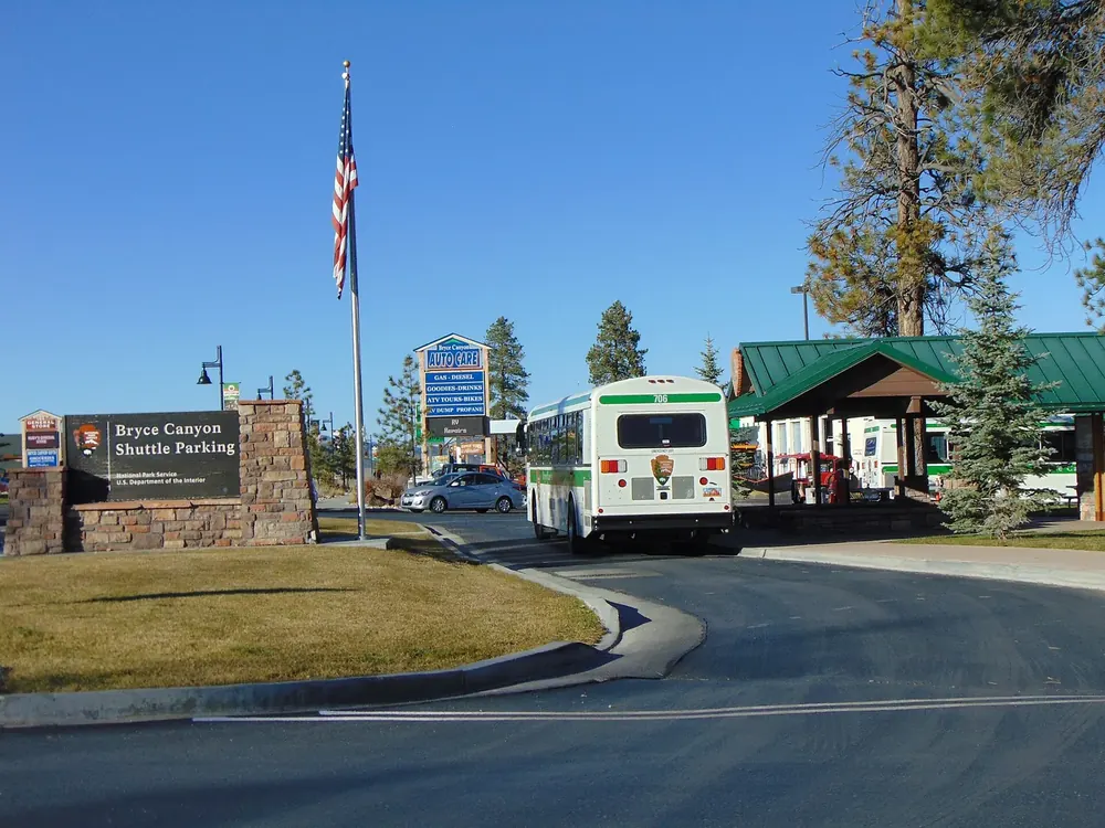 Bryce Canyon shuttle stop in Bryce Canyon City: shuttle bus, shelter, flagpole and pines