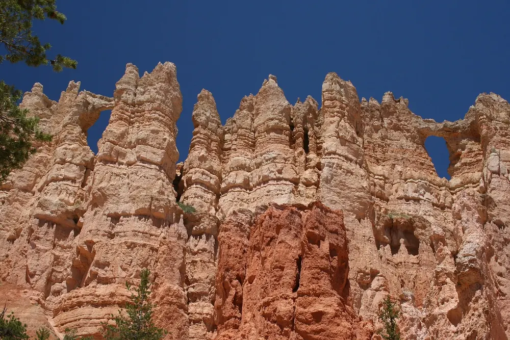 Wall of Windows in Bryce Canyon National Park: a jagged fin of reddish limestone with several window arches against a deep blue sky