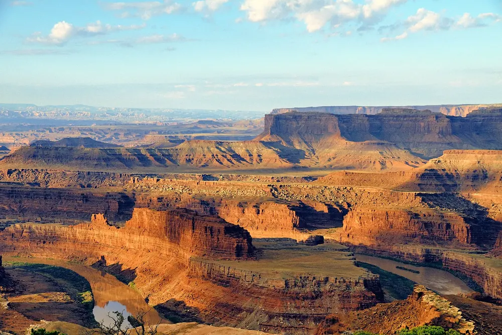 View from Dead Horse Point of a deep river bend between glowing red canyon walls at sunrise