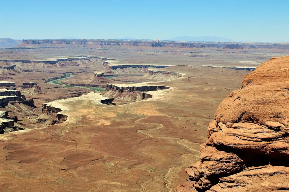 View from Green River Overlook in Canyonlands National Park across wide canyon steps and mesas, the bends of the Green River below