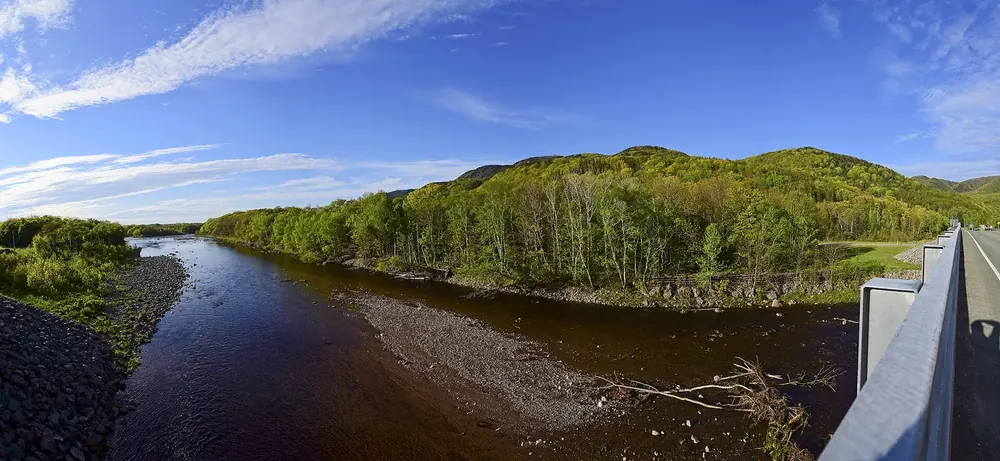 Chéticamp River and the entrance to Cape Breton Highlands National Park seen from the bridge, forested hills