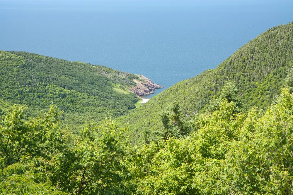 View from the Cabot Trail in Cape Breton Highlands National Park down the forested valley to Fishing Cove on the open sea