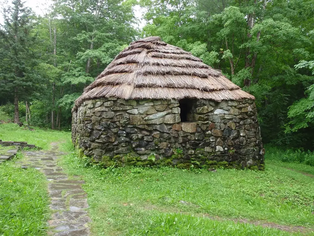 Lone Shieling in Cape Breton Highlands National Park: a replica Scottish crofter’s hut of fieldstone with a thatched roof, surrounded by broadleaf forest