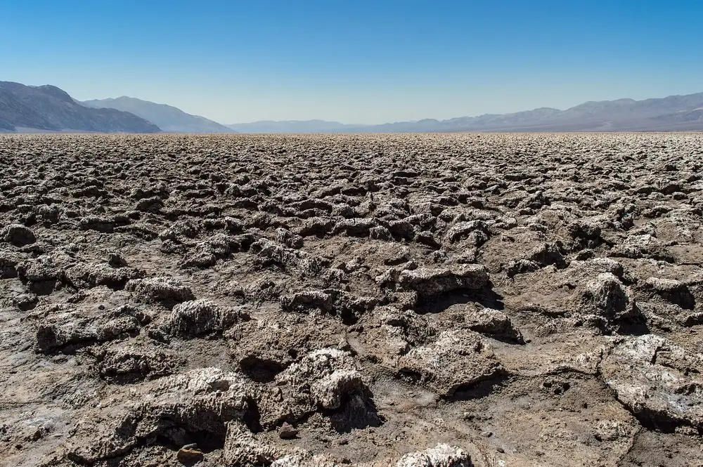 Devils Golf Course in Death Valley National Park: jagged, sharp-edged lumps of salt stretching to the horizon, with bare mountain ranges behind
