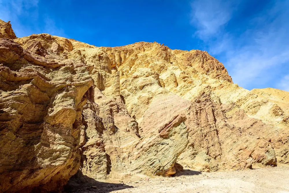 Golden Canyon in Death Valley National Park: bright yellow, eroded rock walls under a deep blue sky with thin veils of cloud