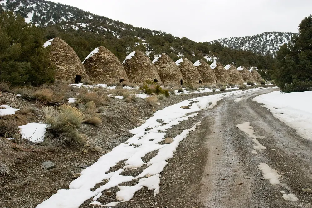 Wildrose Charcoal Kilns in Death Valley National Park: a row of beehive-shaped stone charcoal kilns beside a snowy gravel track