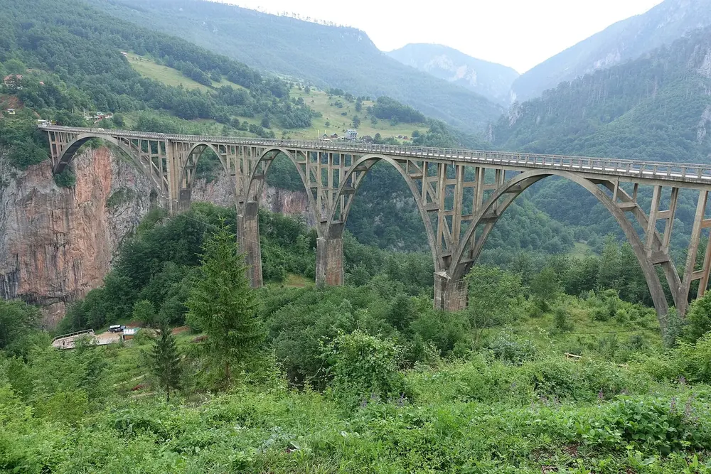 Đurđevića Tara Bridge: a concrete bridge with several arches over the wooded Tara Canyon, green mountain slopes behind