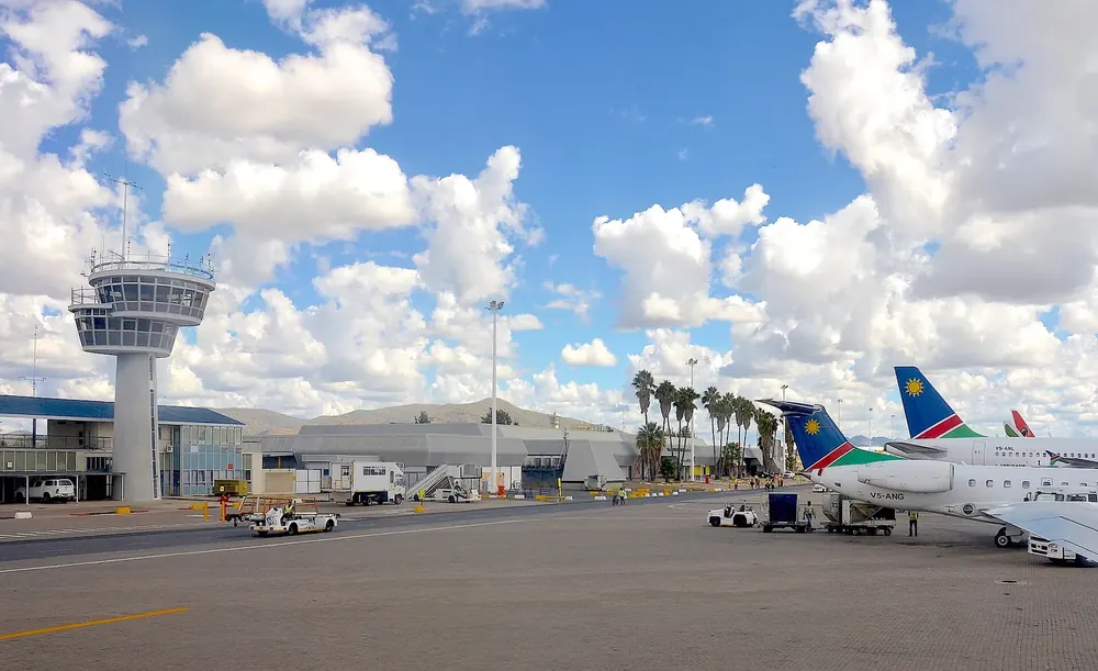 Hosea Kutako International Airport: control tower, terminal and aircraft on the apron under cumulus clouds
