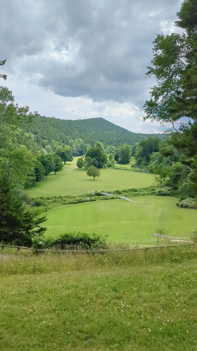 Golf course in Fundy National Park: green fairways in a valley between densely forested hills