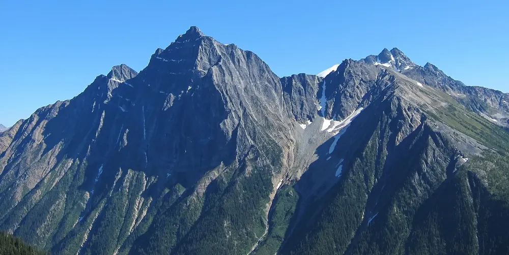Mount Macdonald in Glacier National Park in Canada, in the Selkirk Mountains: steep, dark rock peak with snow gullies under a blue sky