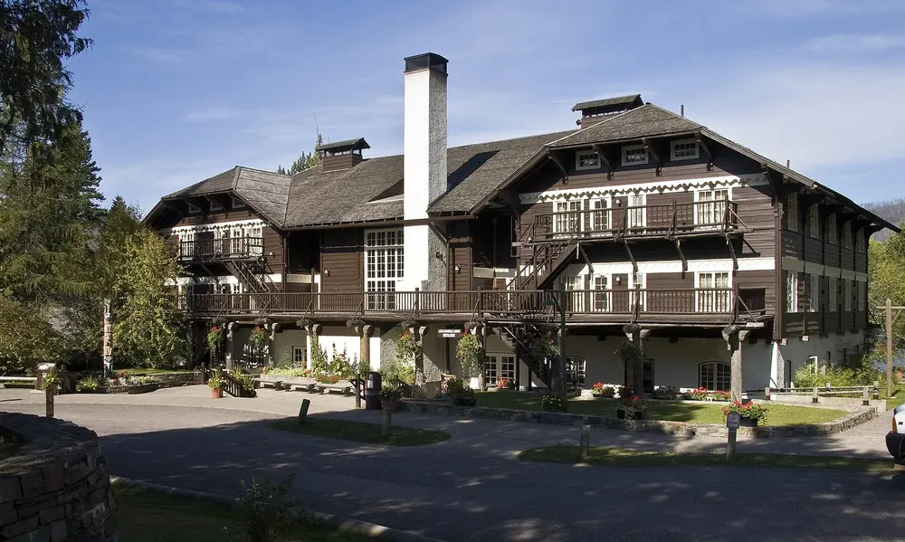 Lake McDonald Lodge: a historic chalet-style wooden building with balconies and a tall stone chimney among trees