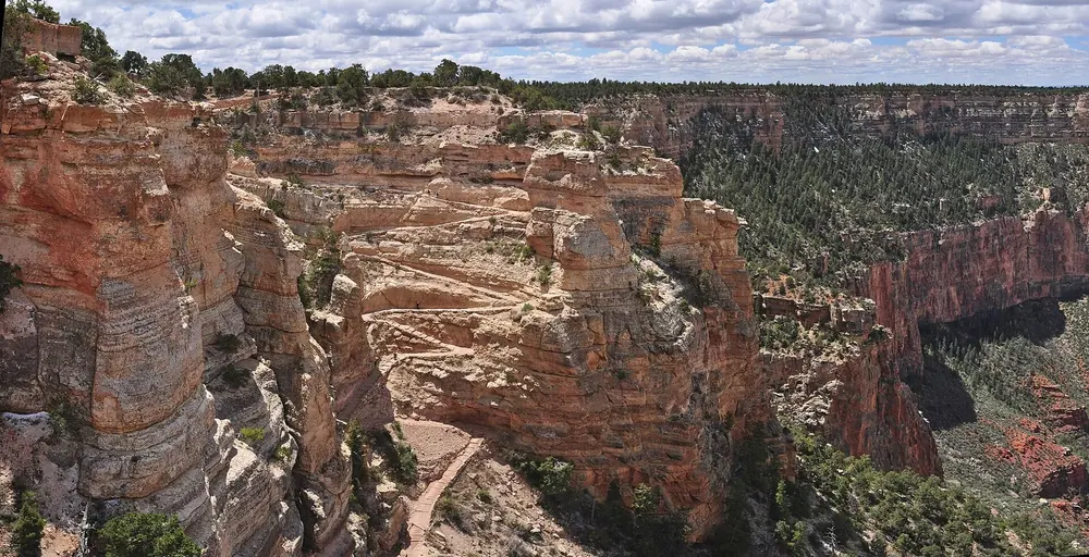 Start of the South Kaibab Trail in Grand Canyon National Park: switchbacks on the cliff face, deeply cut canyons under clouds behind
