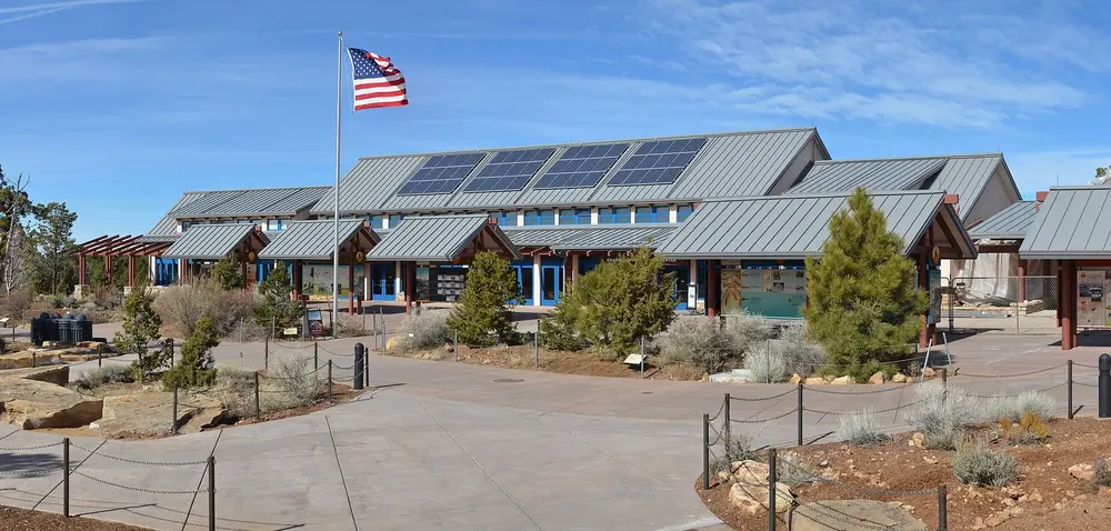 The visitor center of Grand Canyon National Park on the South Rim: low buildings with solar roofs, forecourt and flagpole