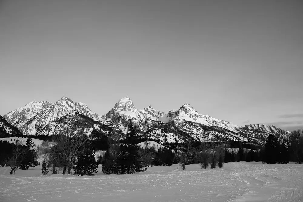 Snow-covered plain at the Taggart Lake Trailhead in Grand Teton National Park in winter, with the snow-capped peaks of the Teton Range behind