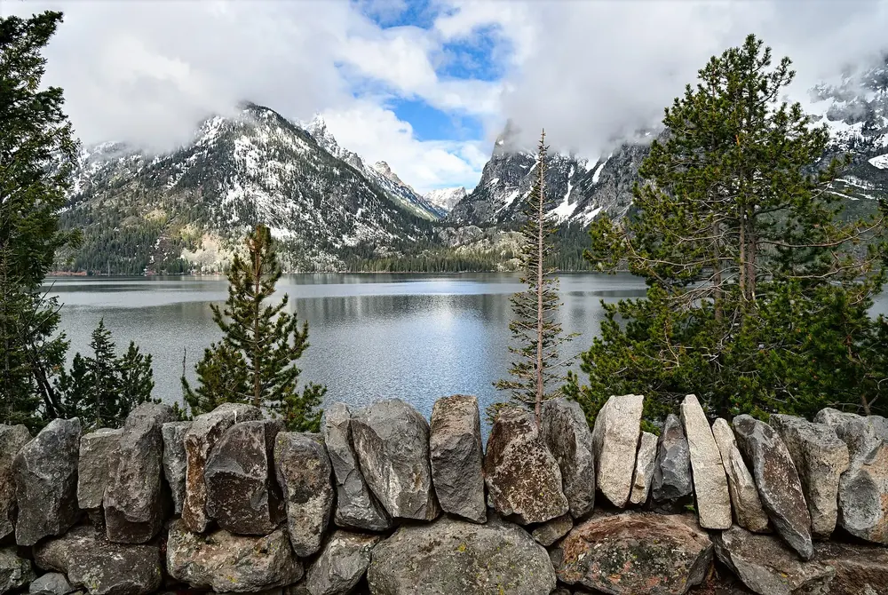 Jenny Lake Overlook in Grand Teton National Park: a natural stone wall in front of the lake, with conifers and the mouth of Cascade Canyon behind