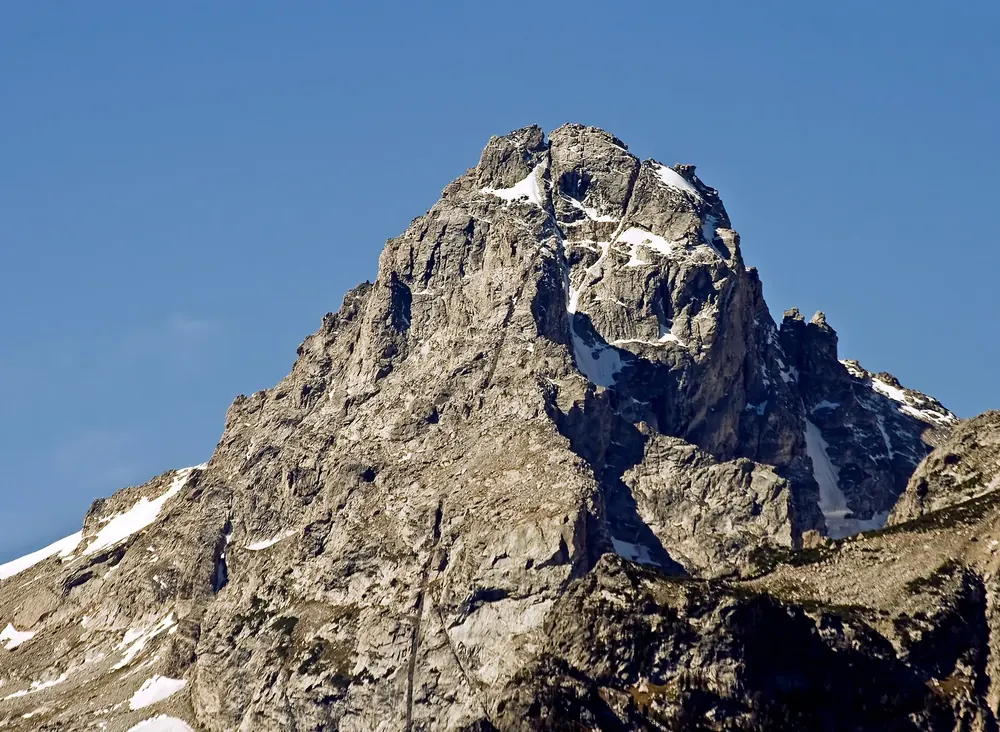 Middle Teton in Grand Teton National Park, from the Teton Point viewpoint: a rocky summit with remnants of snow against a deep blue sky