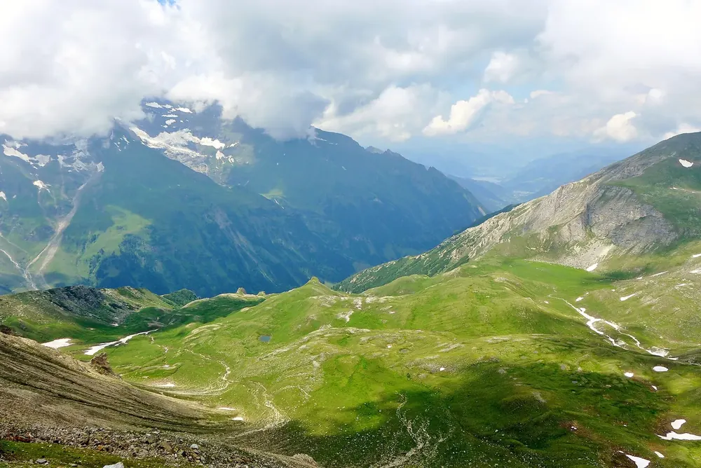 View from the lookout tower on the Edelweiss-Spitze near Hohe Tauern National Park down into green alpine valleys and cloud-capped peaks