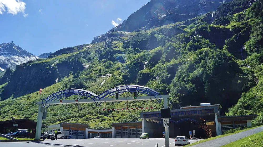 North portal of the Felbertauern Tunnel in the Amertal valley near Hohe Tauern National Park: tunnel entrance with an arched structure below steep green slopes
