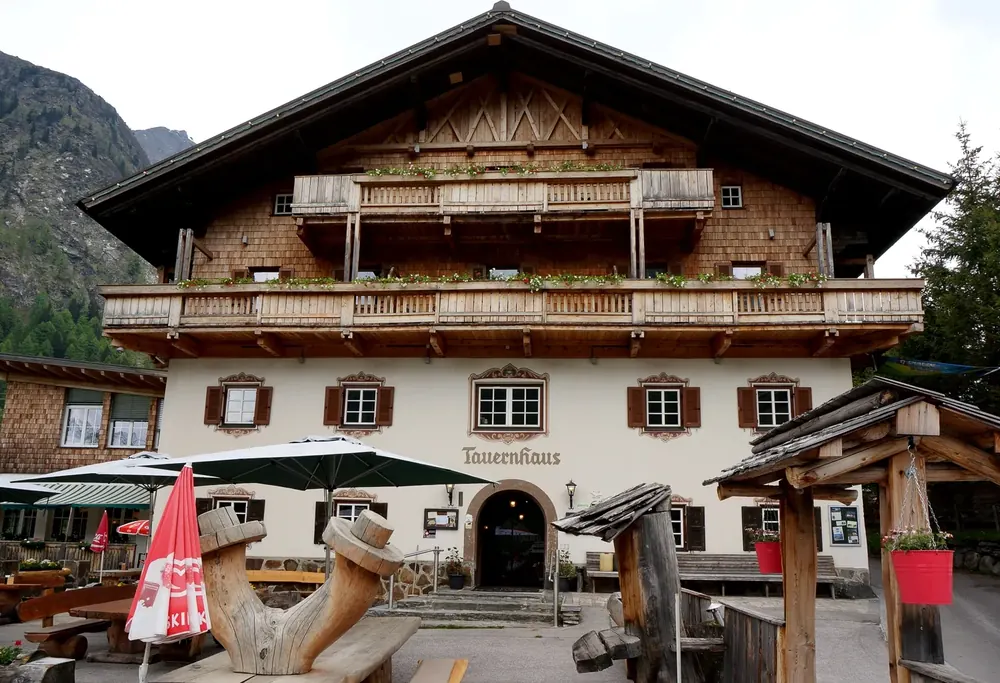 The Matreier Tauernhaus in Hohe Tauern National Park: an alpine inn with wooden balconies and a shingled gable, a terrace with sunshades in front