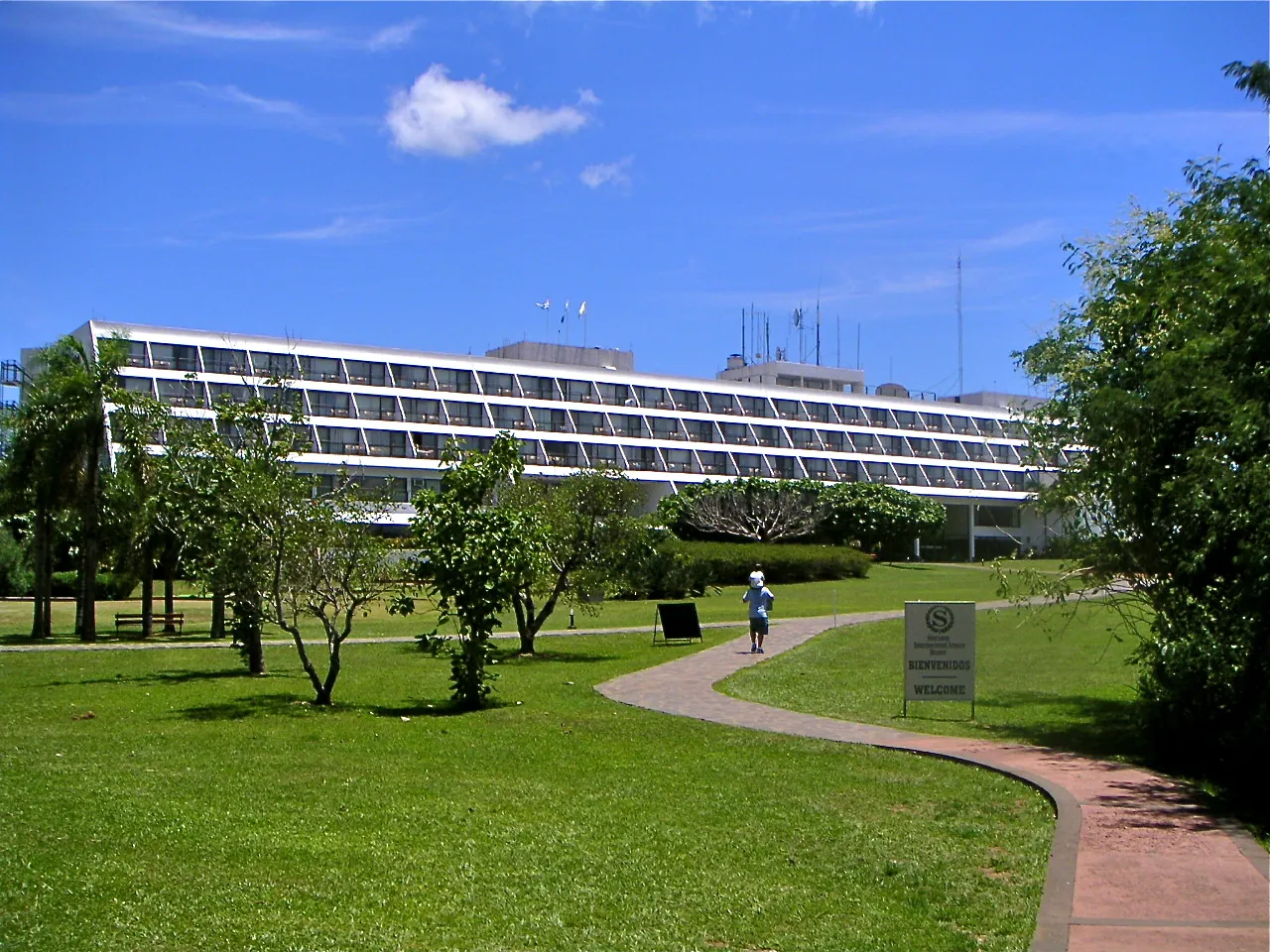 The long hotel building of today's Gran Meliá Iguazú in Iguazú National Park behind a lawn with trees and a curving path