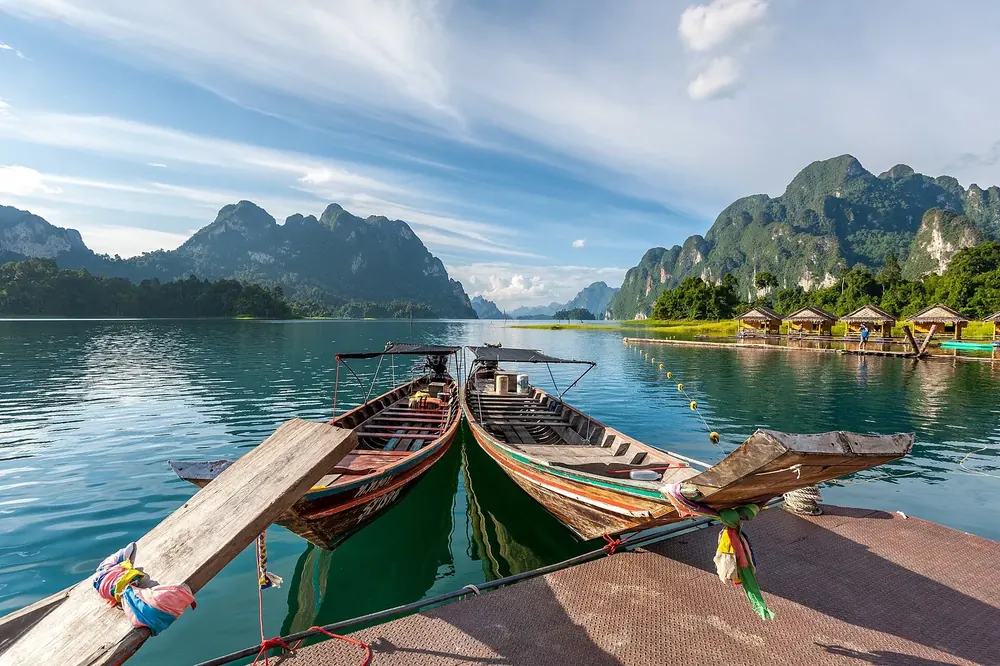 Cheow Lan reservoir of the Rajjaprabha Dam: longtail boats at the jetty, limestone mountains and raft houses behind