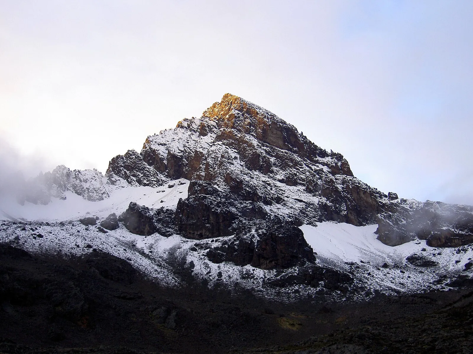 The jagged rock peaks of Mawenzi in Kilimanjaro National Park under fresh snow, the highest point catching the first sunlight