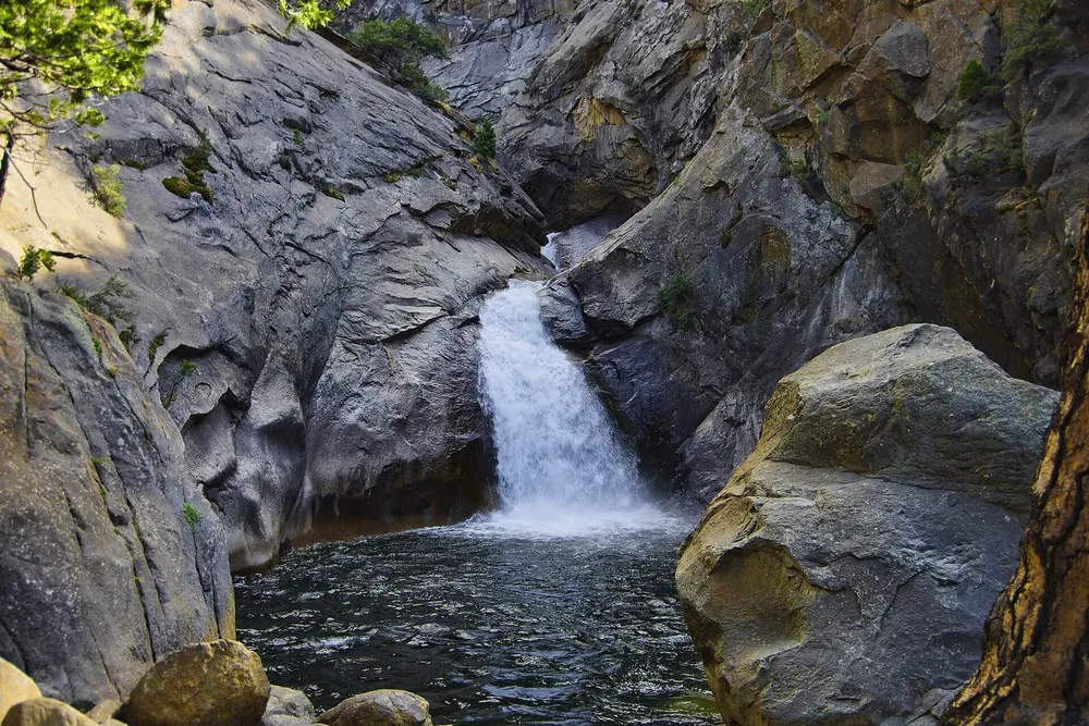 Roaring River Falls in Kings Canyon National Park: the waterfall plunges through a narrow granite gorge into a dark green pool between boulders
