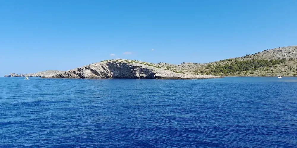 The Kornati islands near Piškera in Kornati National Park: bare, rocky islands with maquis above a deep blue sea, Piškera in the background.