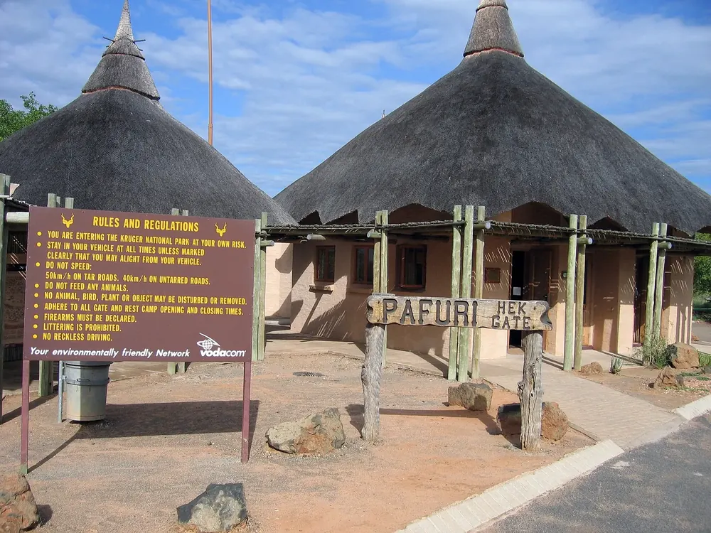 Pafuri Gate, the northern entrance of Kruger National Park: two thatched round buildings with a wooden sign and a rules board
