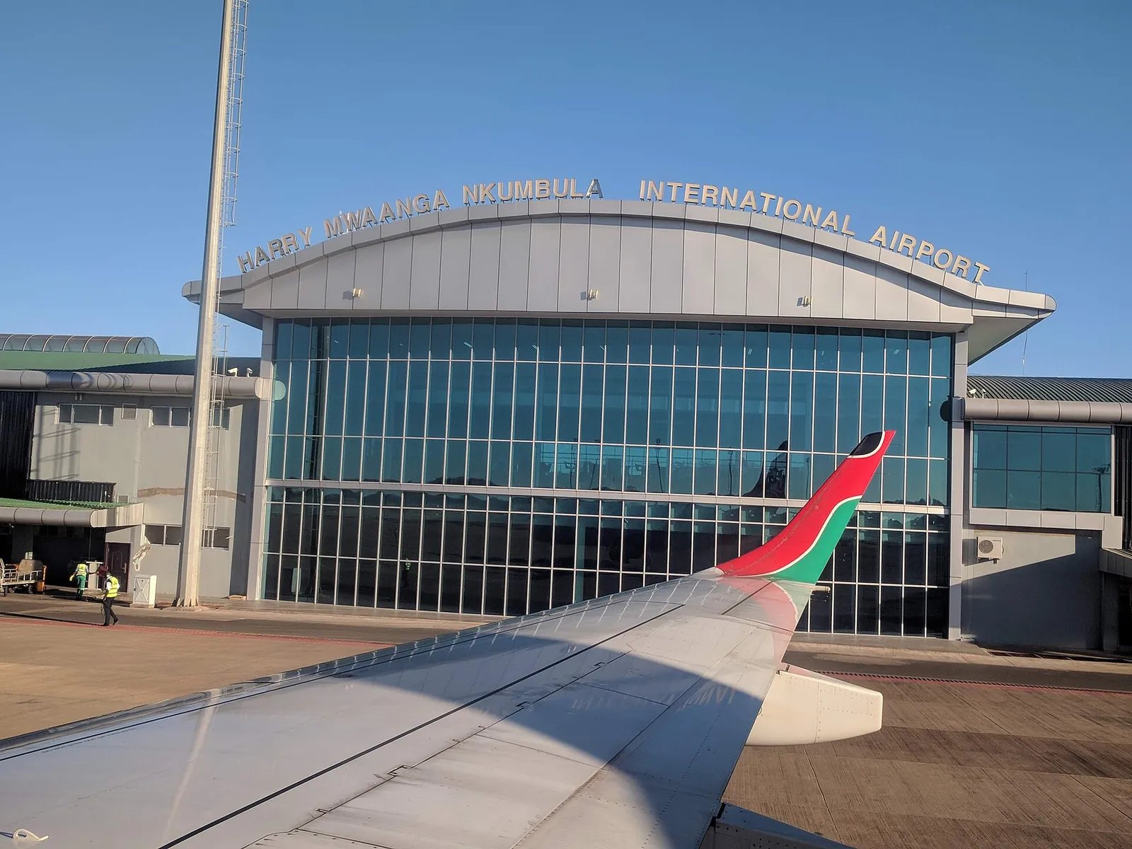Terminal of Harry Mwaanga Nkumbula International Airport in Livingstone with its glass front and lettering, an aircraft wing in front