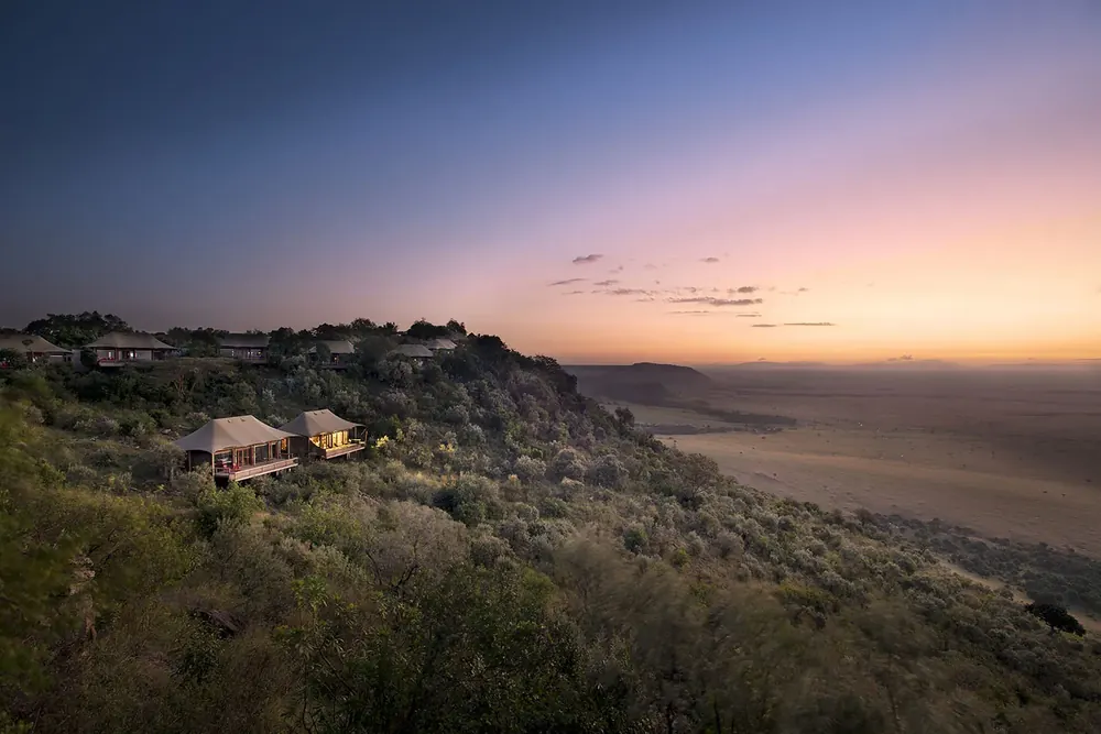 Evening light on the Oloololo Escarpment in the Maasai Mara: a tented lodge on the bushy slope high above the wide Mara plain